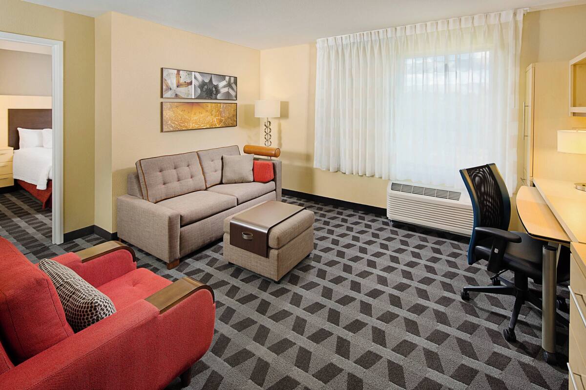 Une chambre d’hôtel avec un canapé, un fauteuil, un bureau et un lit.