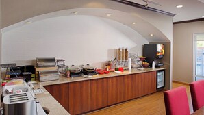 Eine Küchenzeile mit integriertem Grill, einem Kühlschrank und einer Kaffeestation.