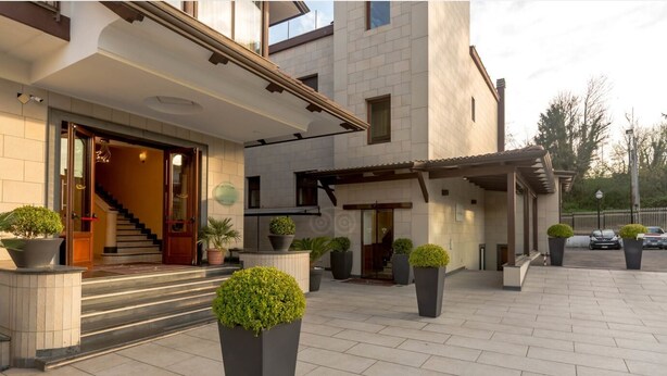 Un edificio moderno con una entrada imponente, una escalera y plantas en macetas.