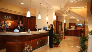 Zona de recepción de hotel con mostrador de madera, un mostrador de recepción y área de bar.