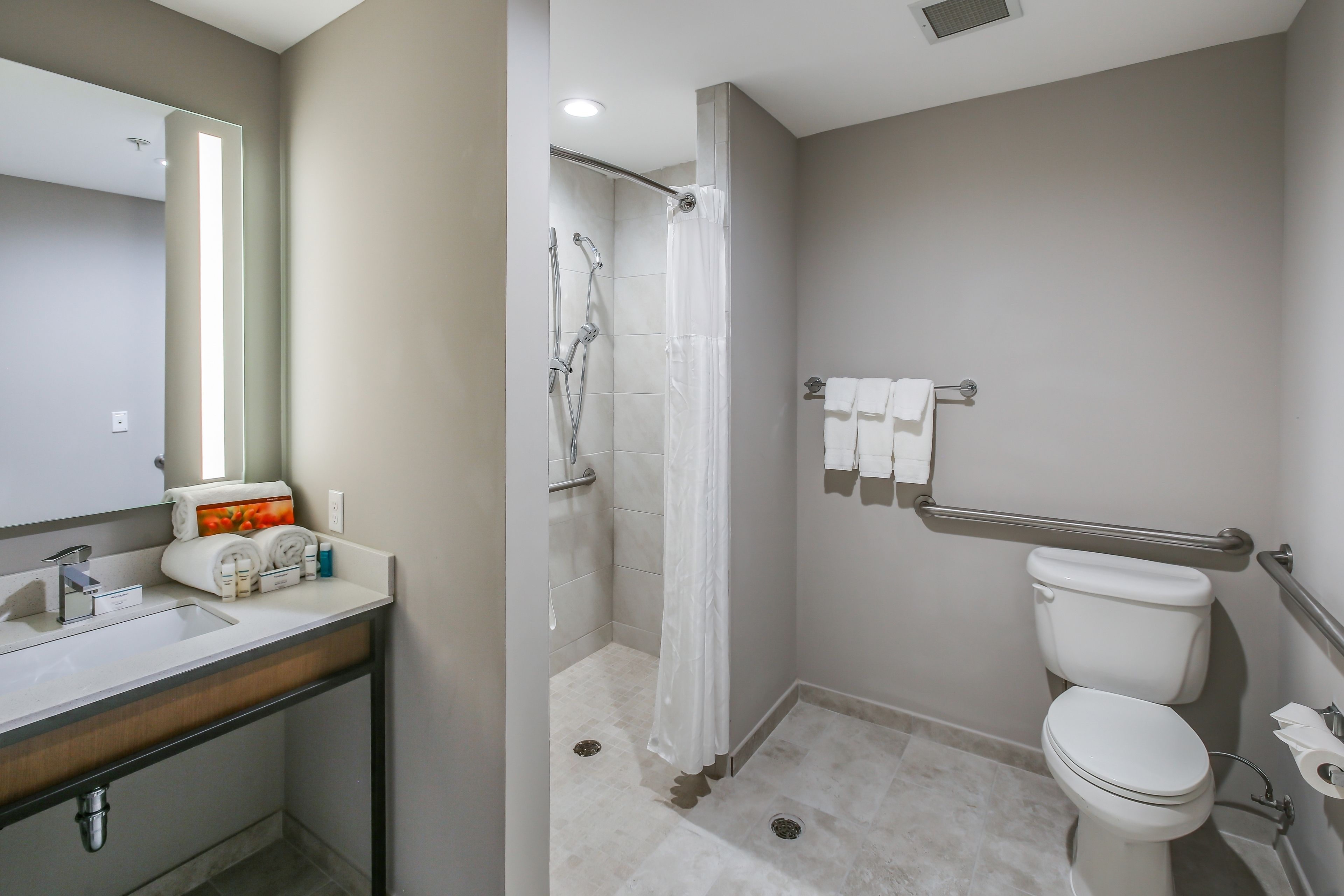A modern bathroom with a sink, toilet, shower, and a towel rack.