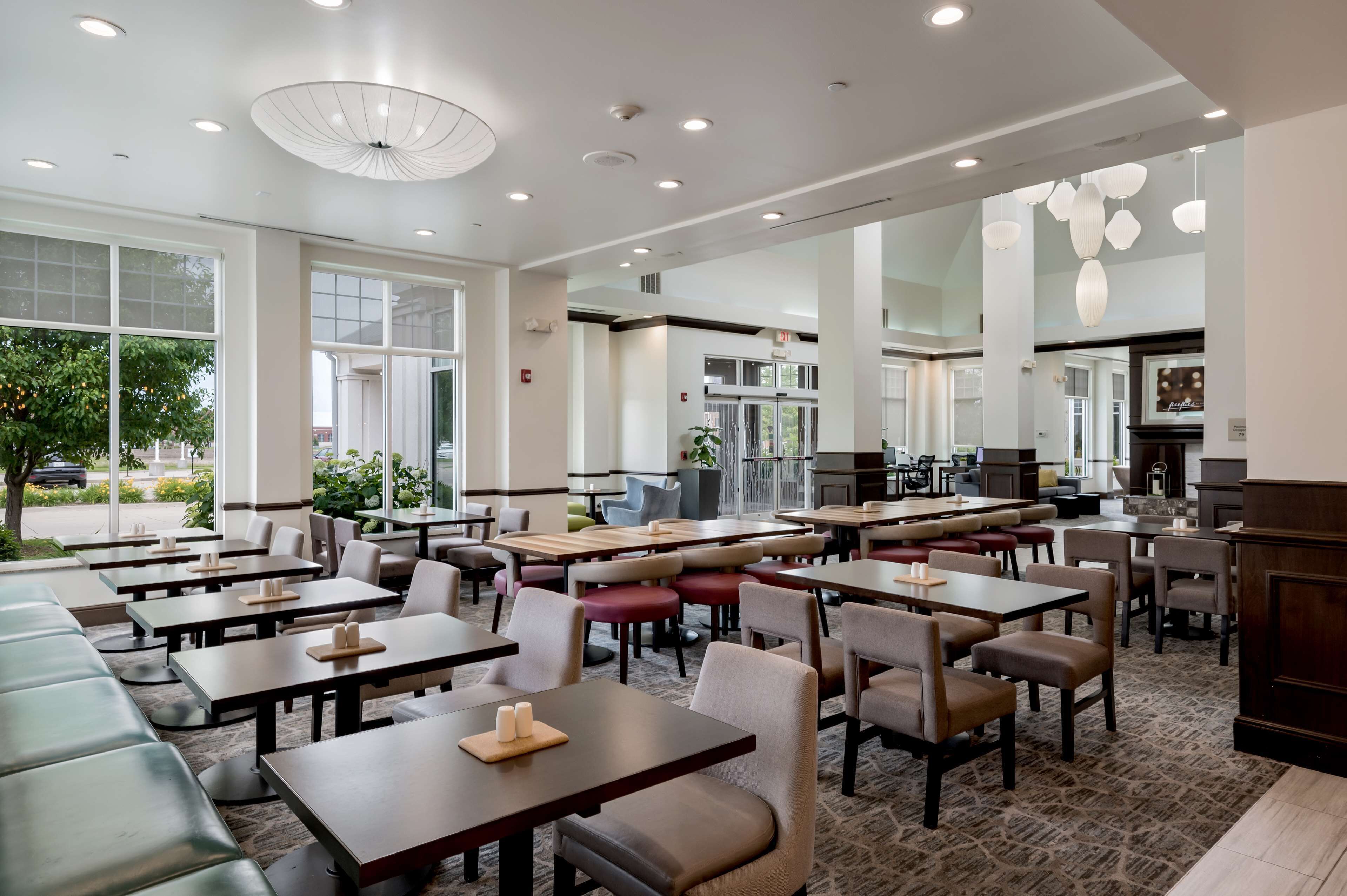 A spacious restaurant with high ceilings, large windows, and a variety of seating options including tables and booths.