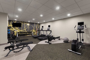 Un gimnasio con cintas de correr, mancuernas y pelotas de ejercicio.