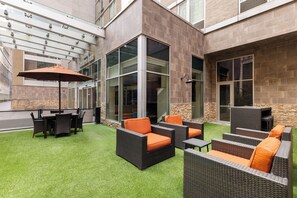 An outdoor patio area with wicker furniture and a glass door leading to the interior.