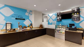 A hotel reception area with a blue wall, a counter with various items, and a coffee machine.