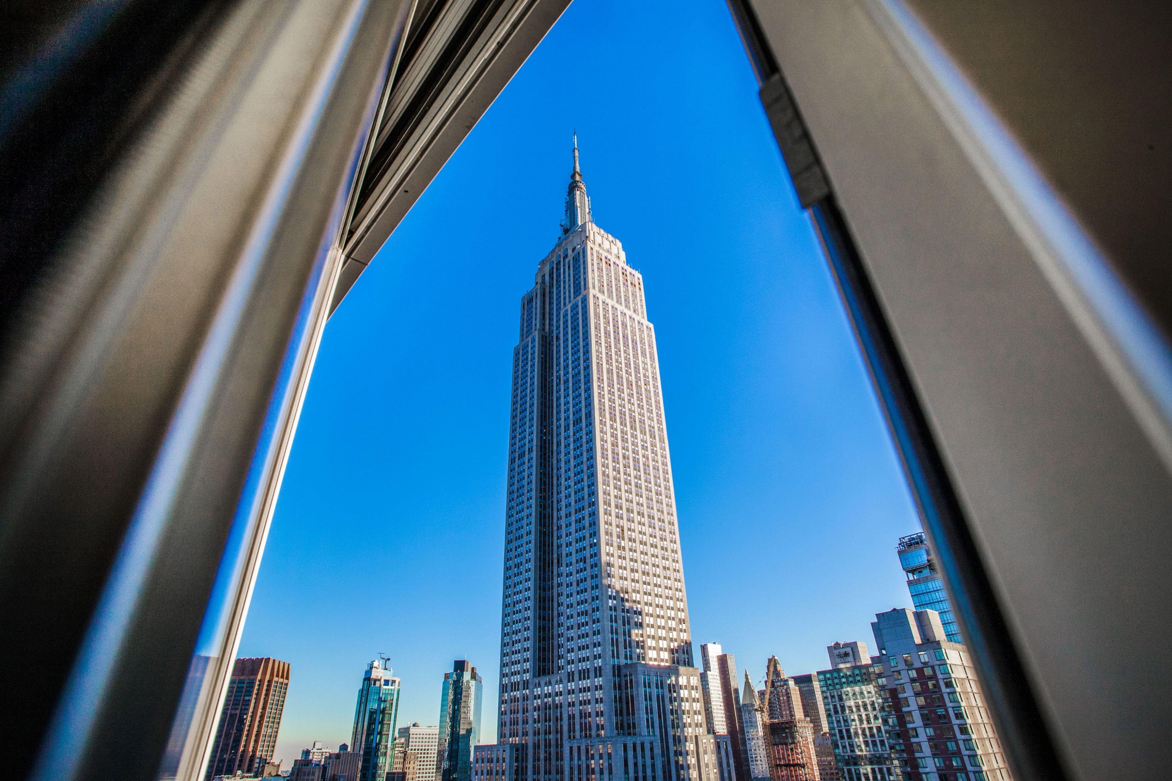 Un edificio alto con aguja, rodeado de otros edificios.