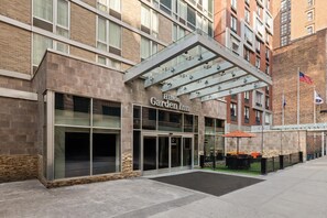 A Hilton Garden Inn with a modern entrance, large windows, and a covered outdoor area with seating. - Hilton Garden Inn New York/West 35th Street (New York)