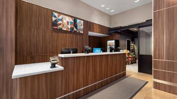 A hotel reception desk with a modern design, a digital kiosk, and a minibar.