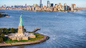 De Vrijheidsbeeld op Liberty Island met de skyline van New York in de verte.