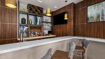 Uma área de bar com interior em madeira, bancada branca e banquetas.