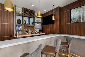 Zona de bar con interior de madera, una encimera blanca y taburetes.