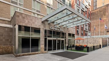 A Hilton Garden Inn with a modern entrance, large windows, and a covered outdoor area with seating.
