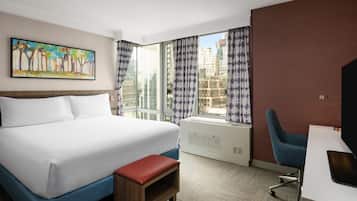A hotel room with a bed, a desk, a chair, a window with curtains, and a painting on the wall.