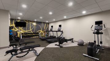 A gym with treadmills, elliptical machines, a bench press, and free weights.