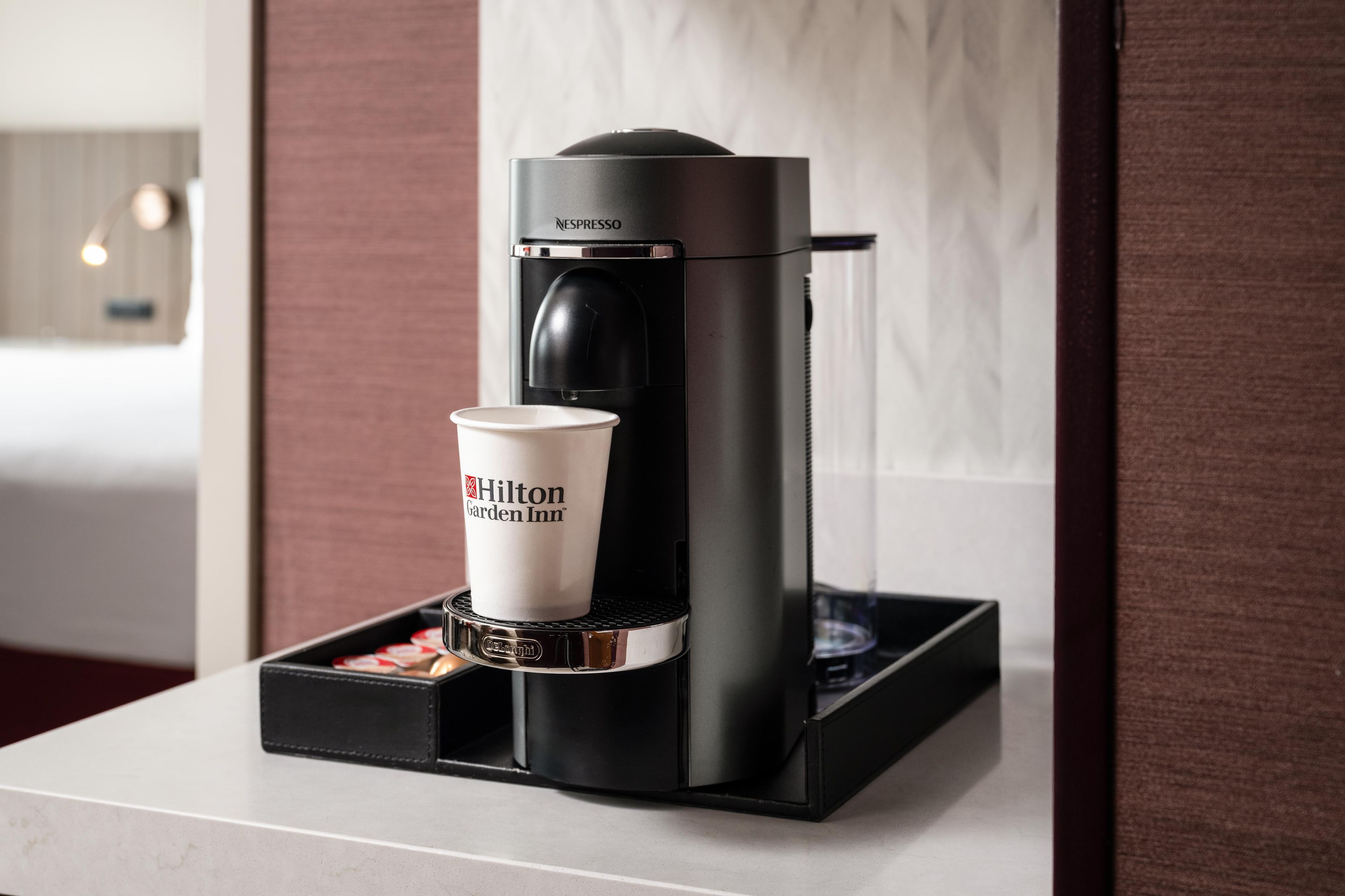 A Nespresso coffee machine with a disposable cup on its drip tray, placed on a countertop.