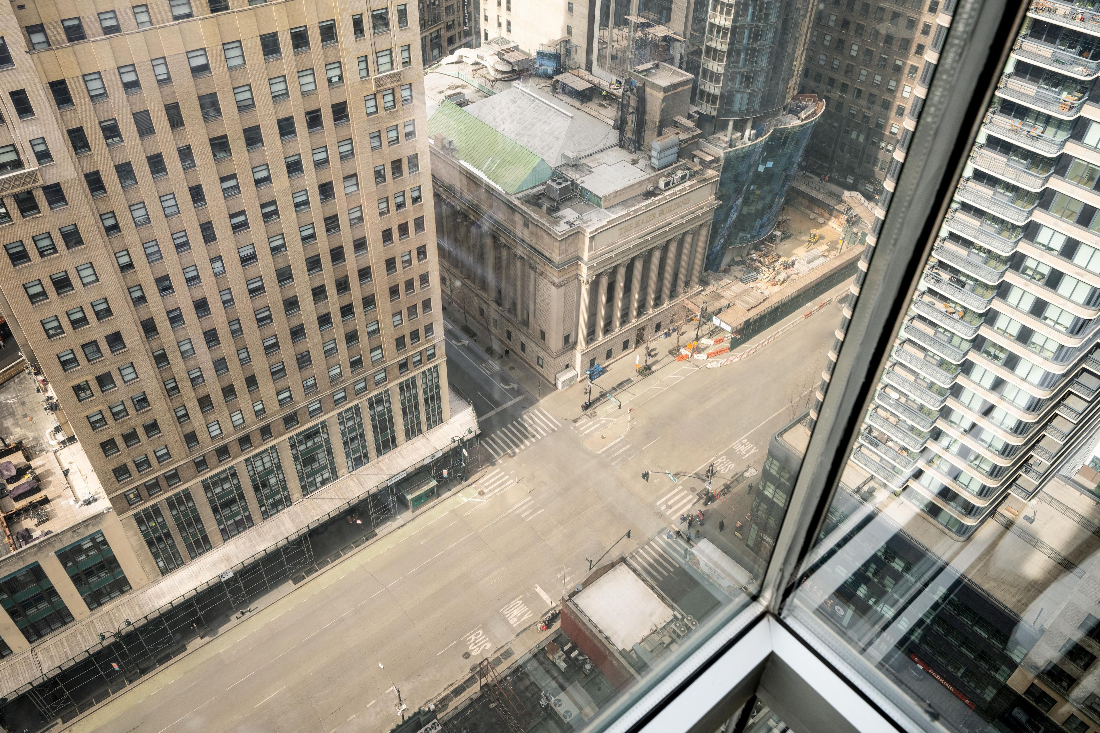 Um edifício alto com uma fachada envidraçada, um pátio central e vista para a rua.