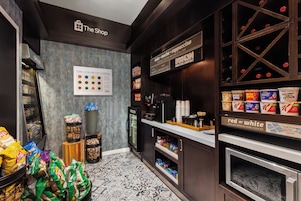 A coffee shop interior with a coffee machine, snack display, and a sign indicating coffee types.