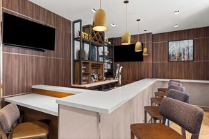 Een moderne bar met een wit aanrecht, barkrukken en een wijnrek.