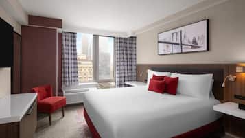 A hotel room with a large bed, a desk, a chair, and a window with curtains.