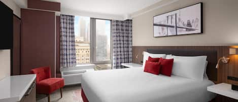 A hotel room with a large bed, a desk, a chair, and a window with curtains.