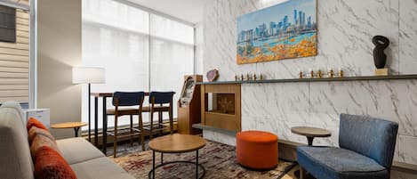 Una sala de estar moderna con un sofá, sillas, una mesa de centro, una chimenea y un cuadro de un paisaje urbano en la pared.