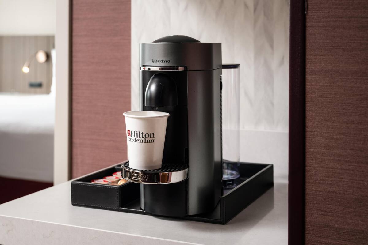 Une machine à café Nespresso avec une tasse à usage unique posée sur un plateau, dans un cadre hôtelier.