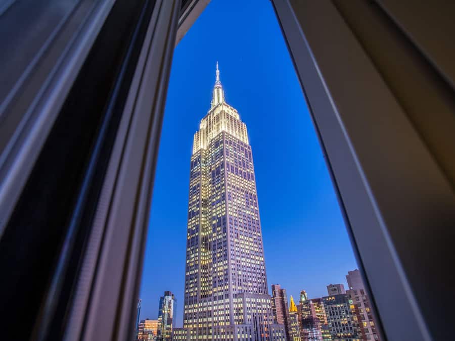 A high-rise building with a distinctive spire, viewed through a window frame.