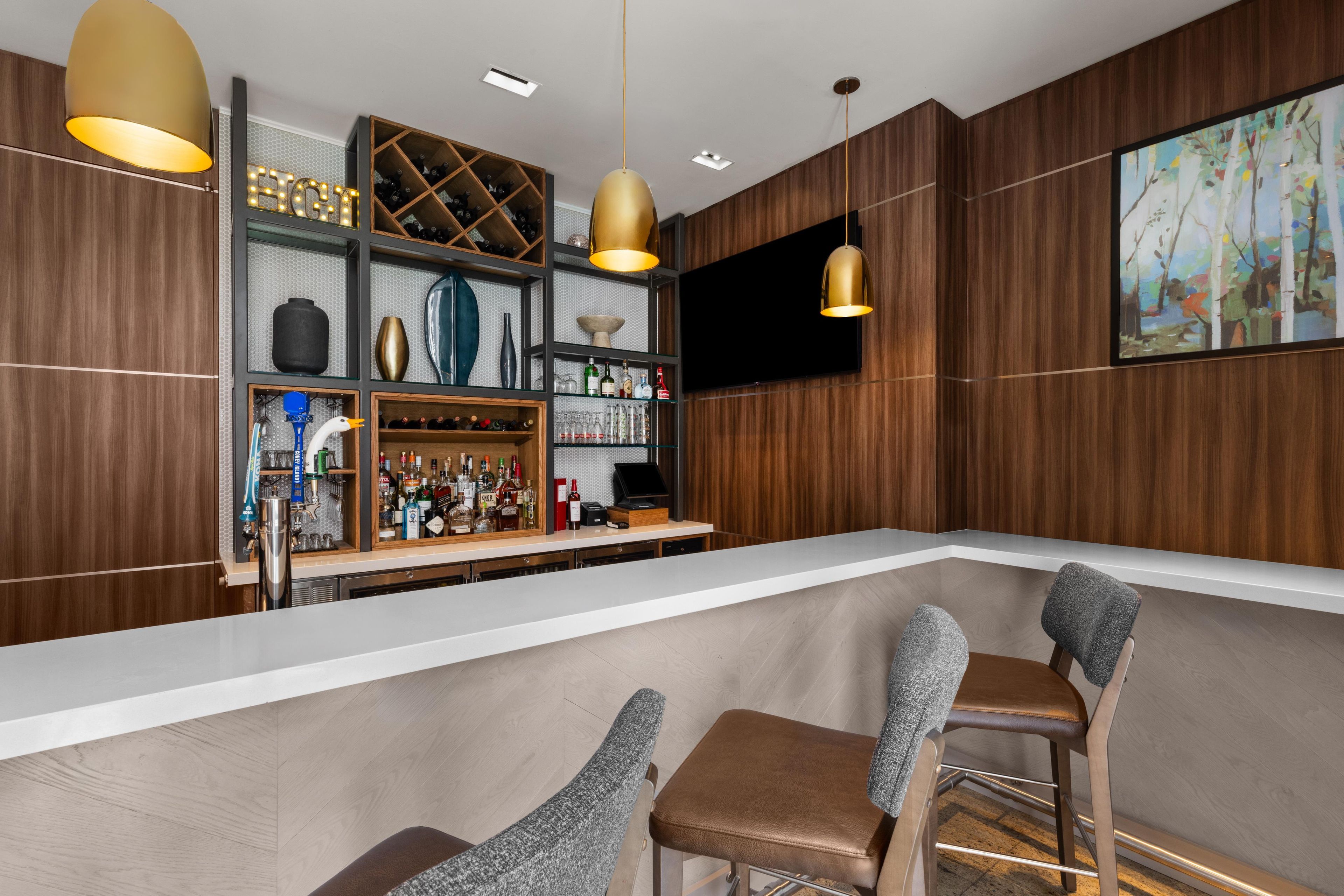 A bar area with a wooden interior, a white countertop, and bar stools.