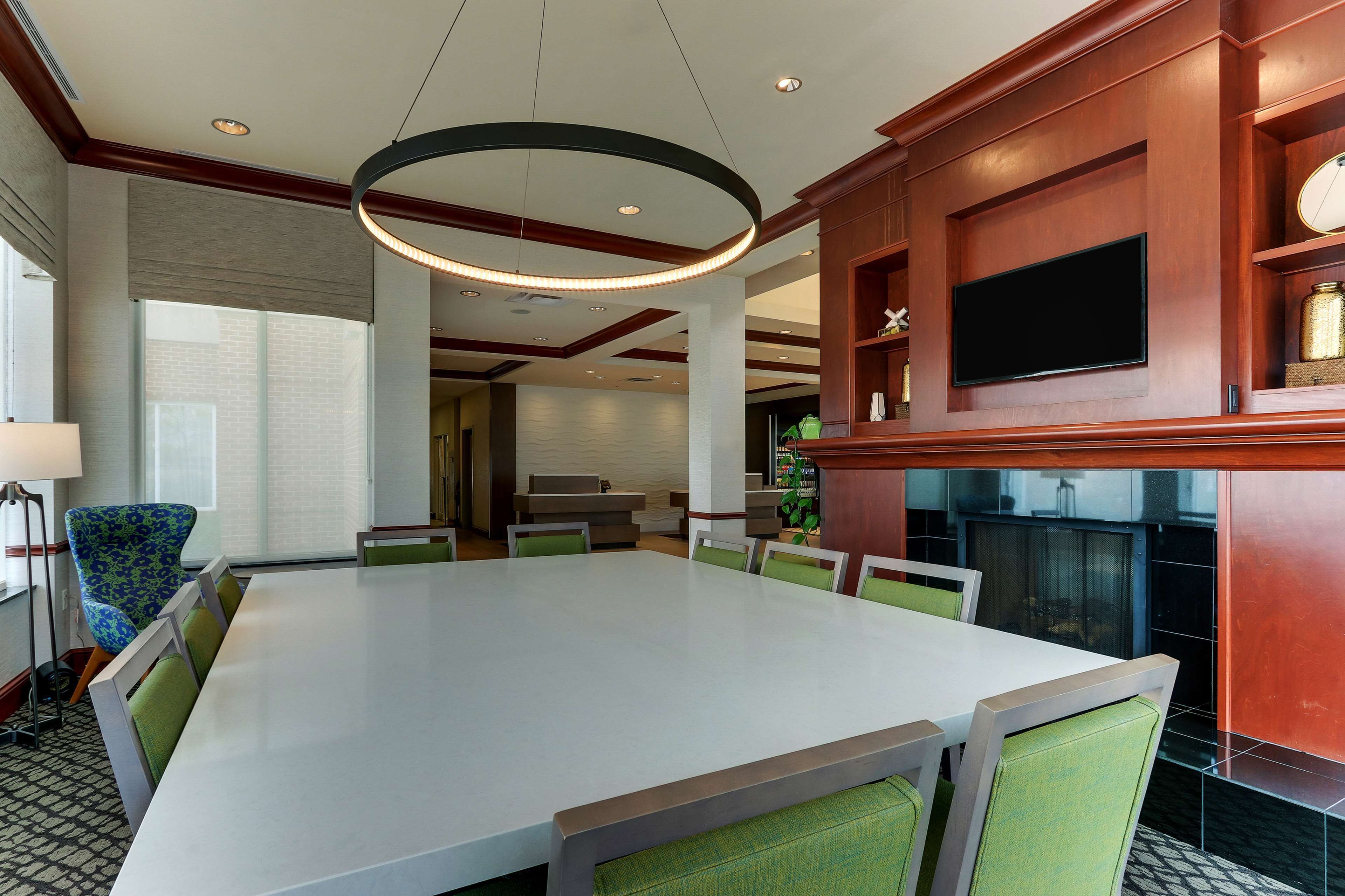 A conference room with a large table, green chairs, a television, and a fireplace.