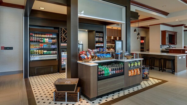 A modern hotel lobby with a bar area, vending machines, and a seating area. - Hilton Garden Inn Indianapolis Airport (Indianapolis)