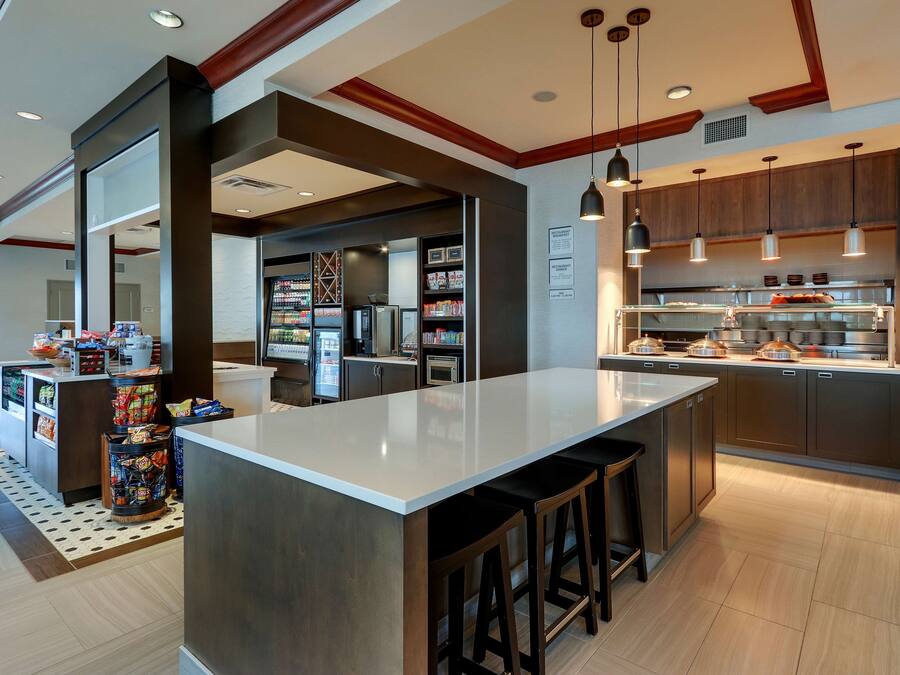 A modern kitchen with a central island, bar stools, and a refrigerator.