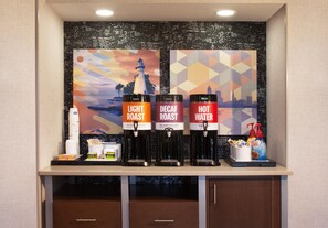Una estación de café con tres dispensadores etiquetados como 'Tueste Suave', 'Tueste Descafeinado' y 'Agua Caliente'.