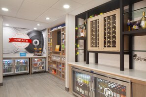 A hotel lobby with a 'Treats' sign, snack vending machines, a wine display, and a 'Welcome to Mentor' sign. - Hampton Inn & Suites Cleveland Mentor (Mentor)