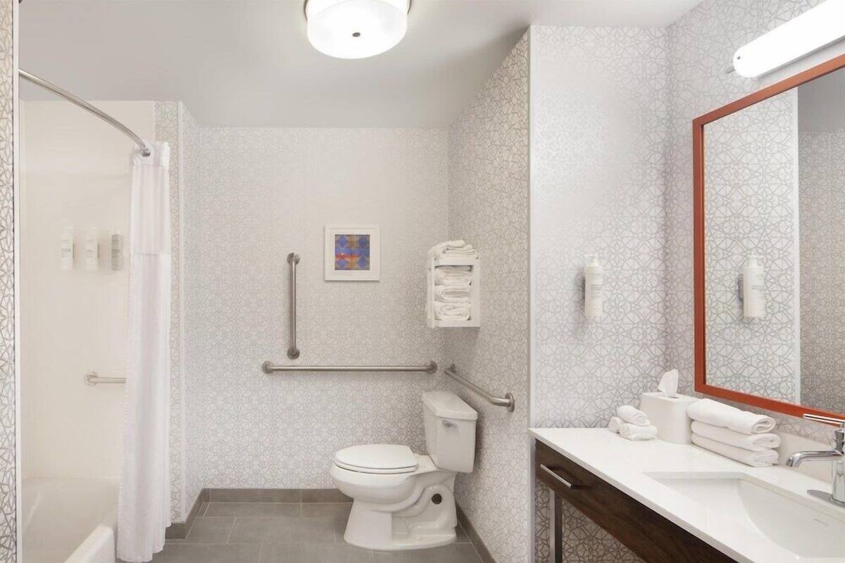 A modern bathroom with a toilet, bidet, and handrails.