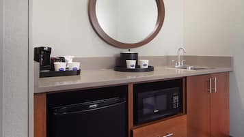 Un bagno moderno con uno specchio rotondo, una macchina da caffè e un lavandino.