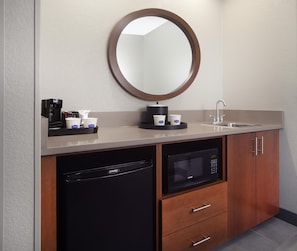 A modern bathroom with a round mirror, a coffee maker, and a sink. - Hampton Inn & Suites Cleveland Mentor (Mentor)