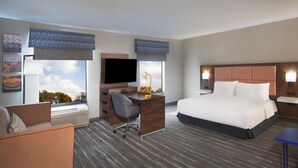 A hotel room with a bed, a desk with a computer, a chair, a TV, and a window with a view of trees. - Hampton Inn & Suites Cleveland Mentor (Mentor)