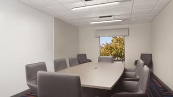 A conference room with a rectangular table, six chairs, and a large window with a view of trees.