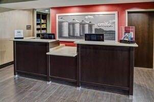 A reception desk with a 'Hilton Honors' sign, a 'Smile' poster, and a 'Motel 8' sign.