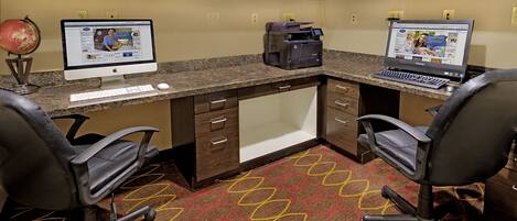 A workspace with two desks, each with a computer, a printer, and office chairs.