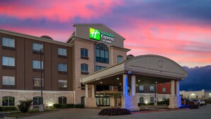 Ein Holiday Inn Express & Suites Gebäude mit Ziegelaußenwand, großen Fenstern und einem überdachten Eingangsbereich.