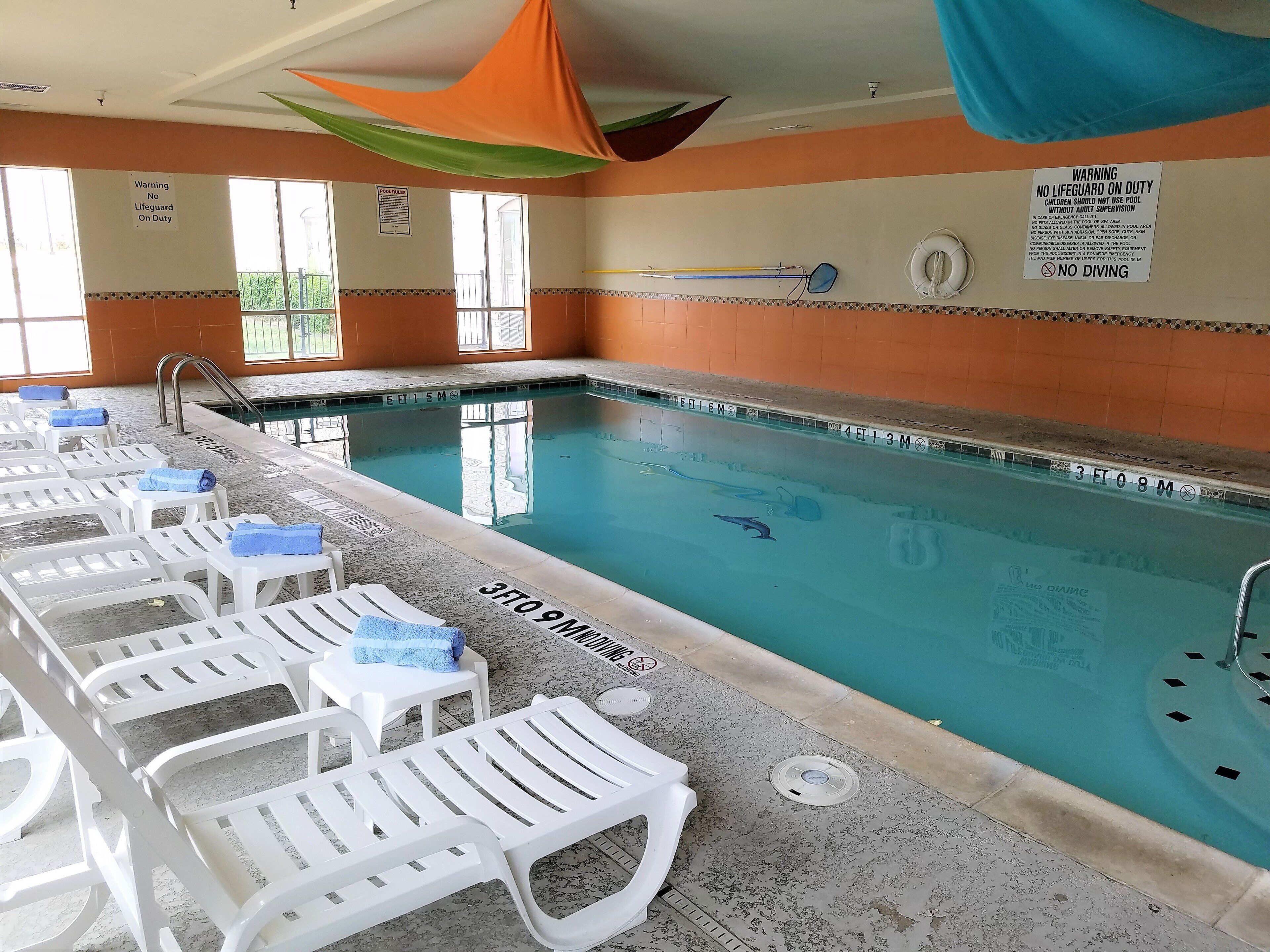 A swimming pool with lounge chairs, safety signs, and a lifeguard warning.