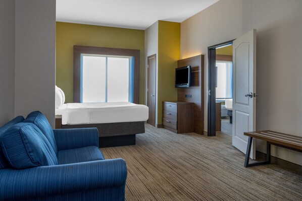 Quarto de hotel com cama, televisão, escrivaninha, cadeira e janela.