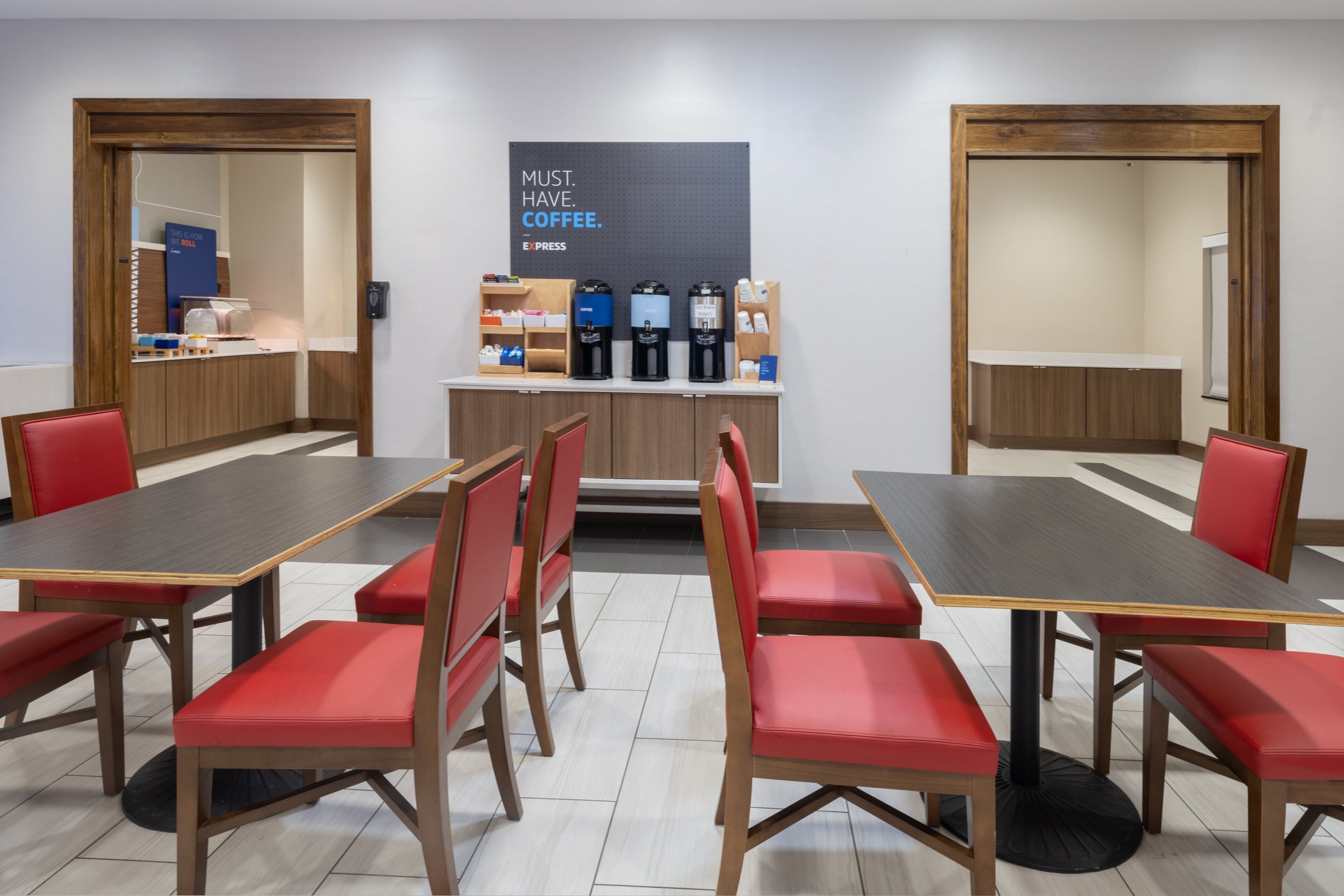 A conference room with a coffee station, red chairs, and a large poster on the wall.