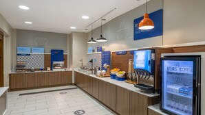 Ein moderner Frühstücksbereich mit Selbstbedienungsstation, Obstauslage und einem Getränkeautomaten.