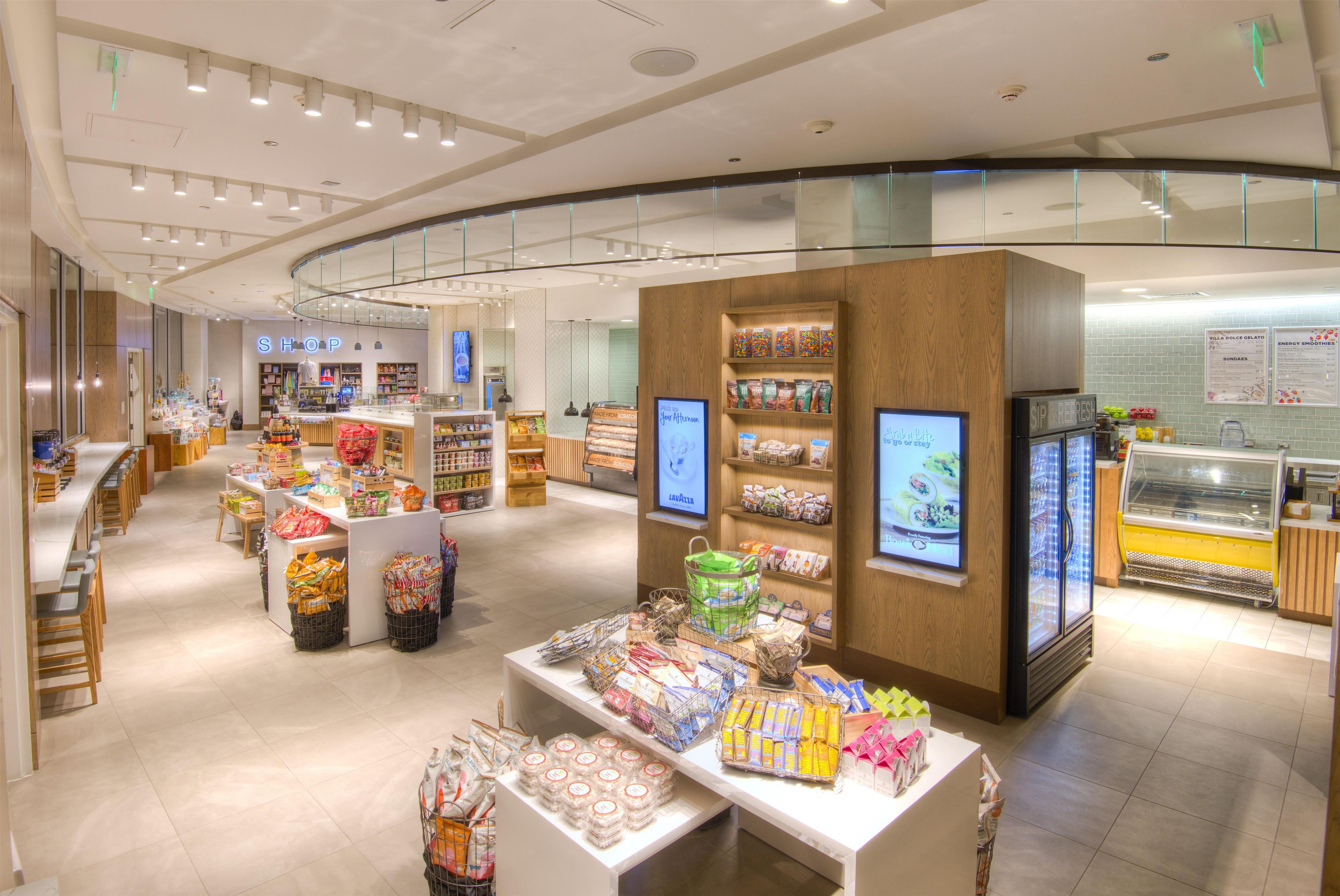 A modern shopping area with a central display, glass railings, and a refrigerated section.