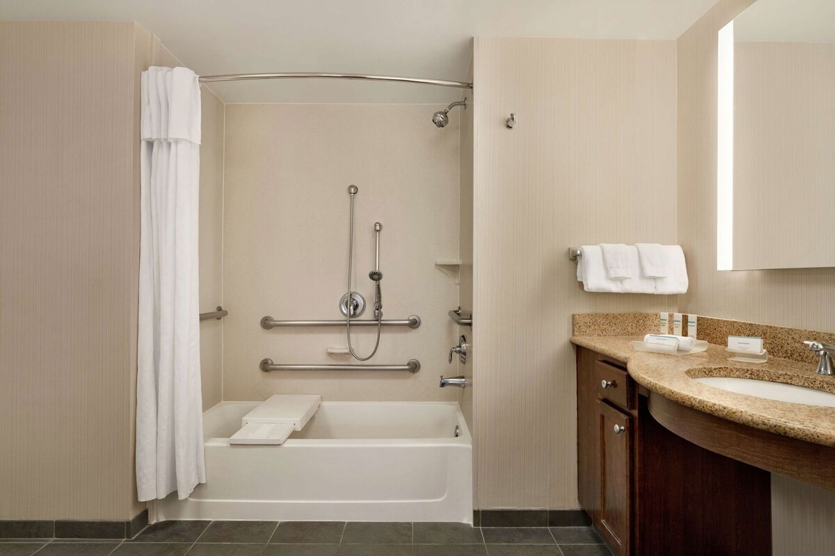 Een badkamer met een badkuip, een douche, een wastafel en een spiegel.