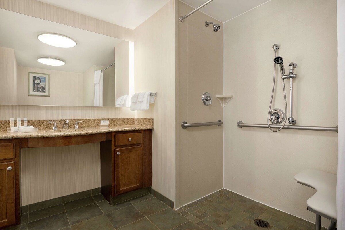 Een hotelbadkamer met een douche, een wastafel met spiegel en een wasbak.