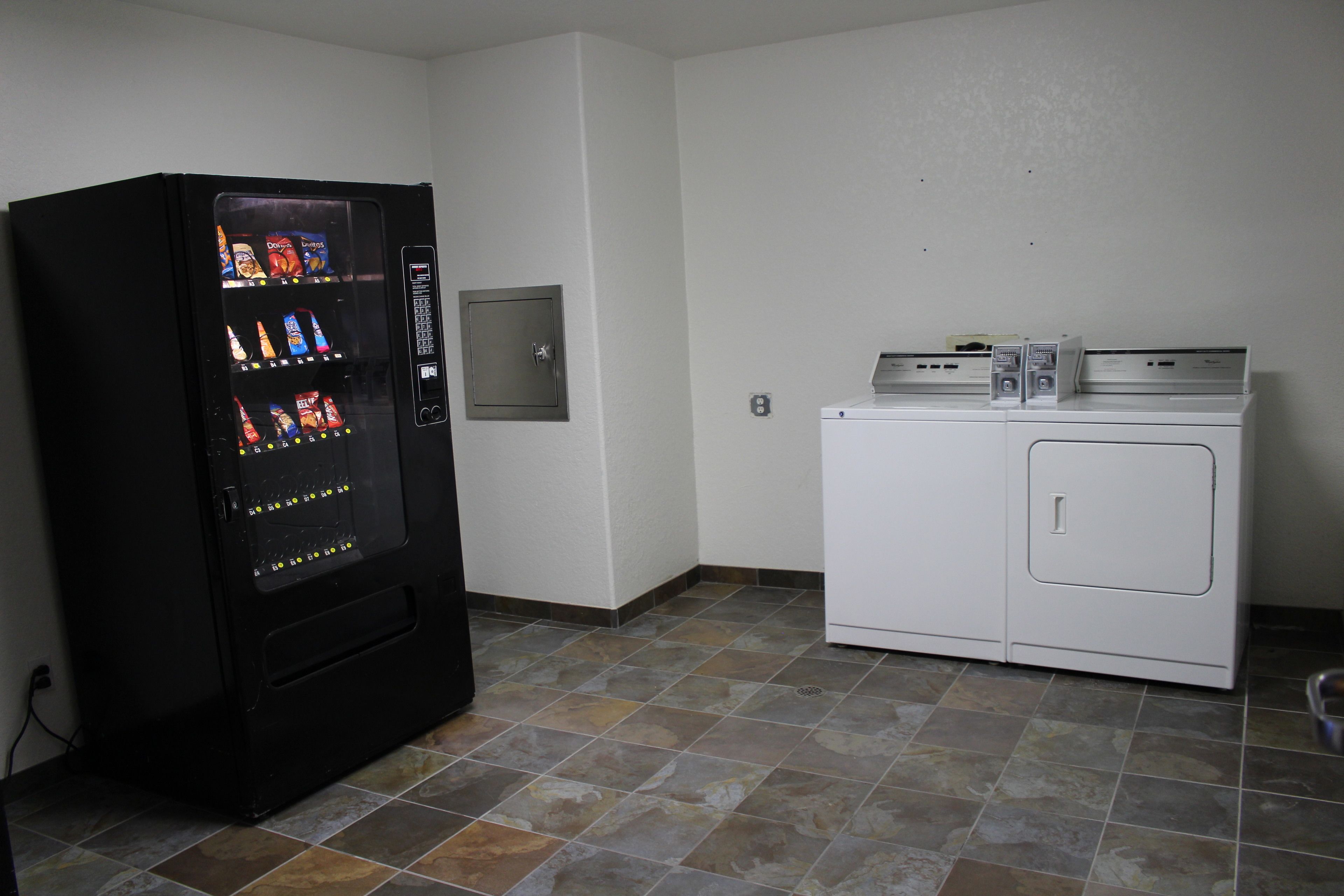 A laundry room with a vending machine and a washer and dryer.