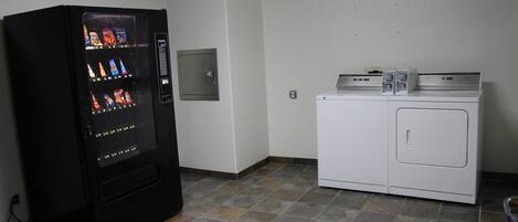 A laundry room with a vending machine and a washer and dryer.
